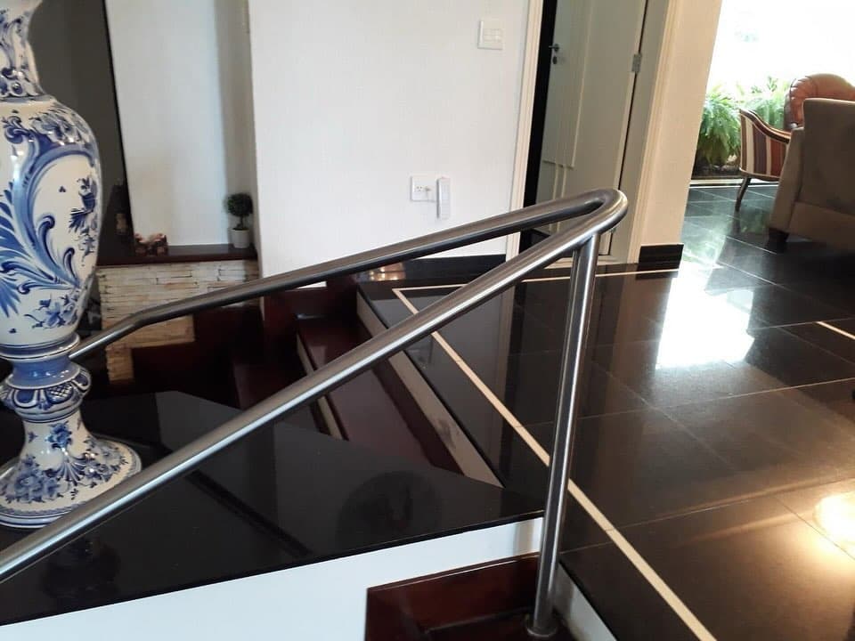 Corrimão em aço inox escovado com extremidade curva em escada interna de piso escuro
