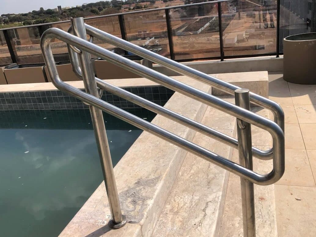 Corrimão em aço inox de dupla altura fixado nos degraus de entrada de uma piscina