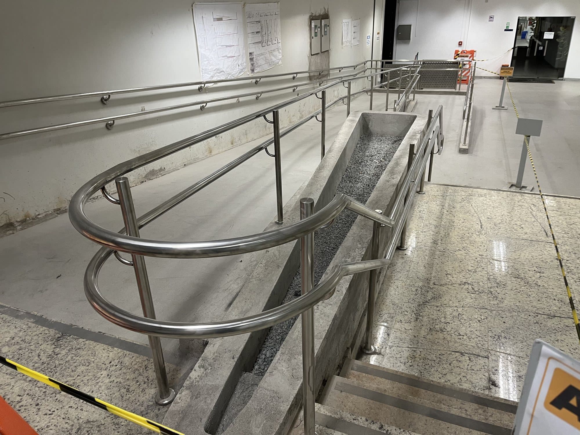 Rampa de acessibilidade com corrimãos duplos em aço inox na parede e na lateral