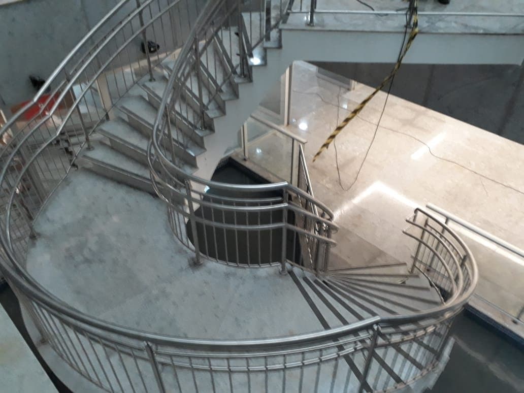 Escada curva de edifício com guarda-corpo em aço inox de balaústres verticais, vista de cima