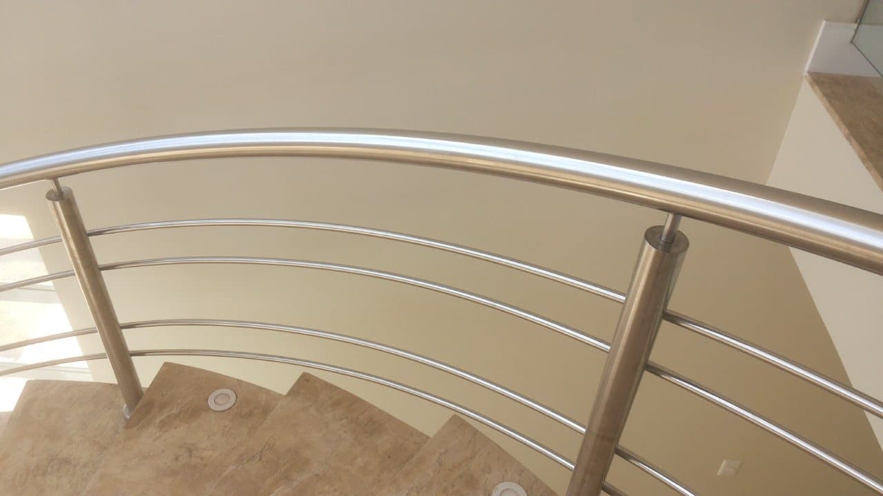 Detalhe do corrimão e dos tubos curvados em aço inox sobre os degraus de mármore