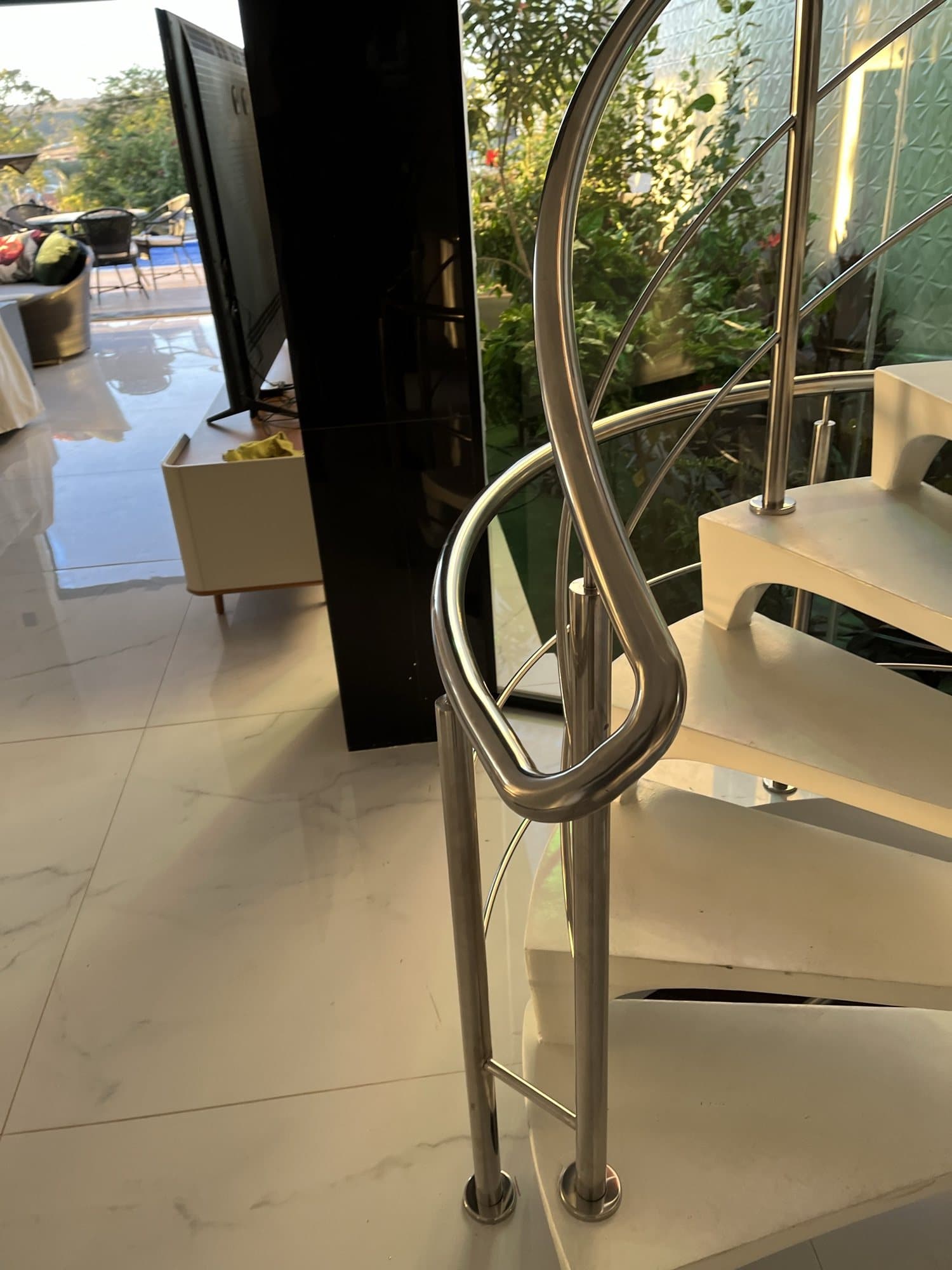 Início do corrimão em aço inox no primeiro degrau da escada helicoidal, com montantes fixados ao piso
