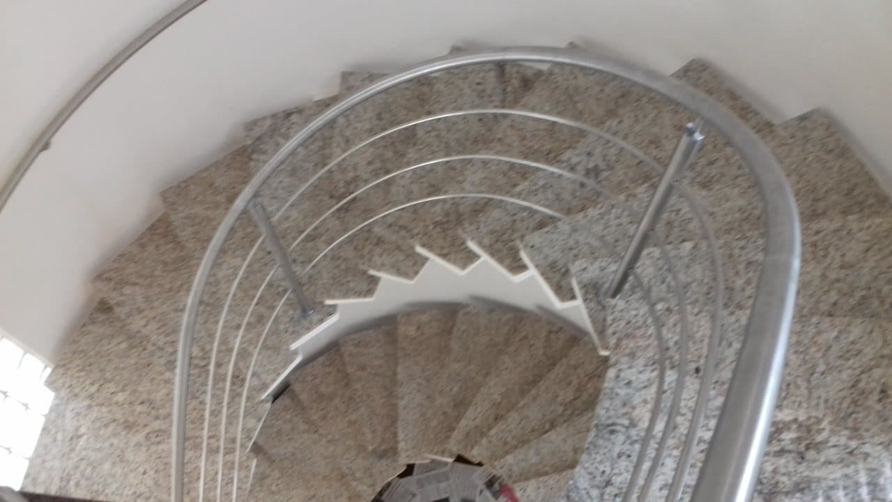 Corrimão e tubos curvados em aço inox acompanhando os degraus da escada helicoidal