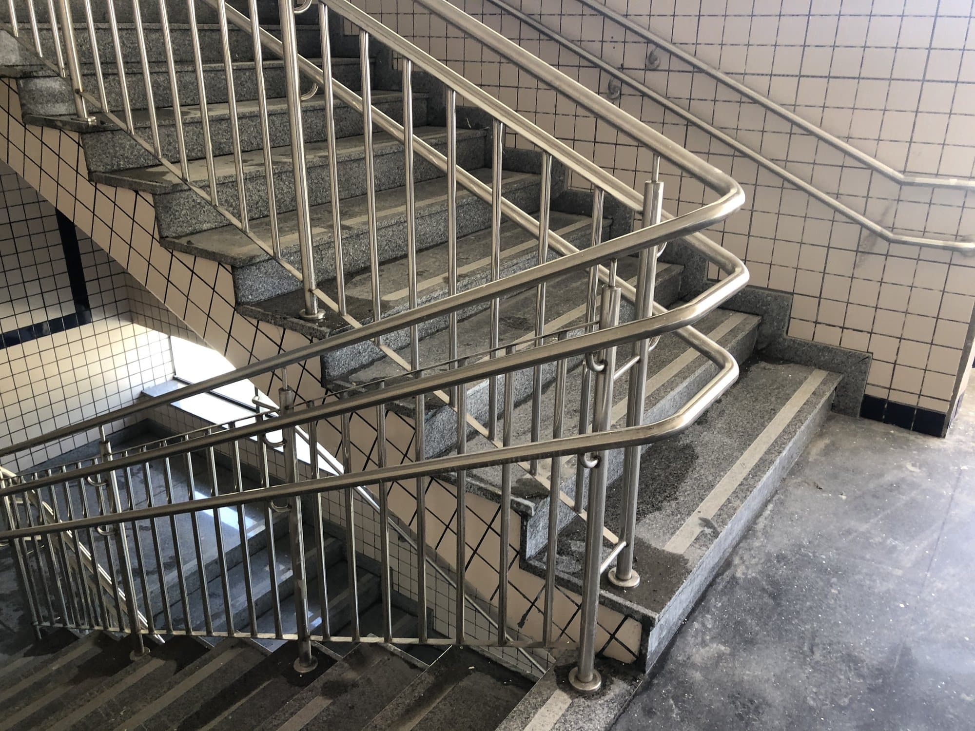 Escada de edifício com guarda-corpo em aço inox de balaústres verticais e corrimão duplo