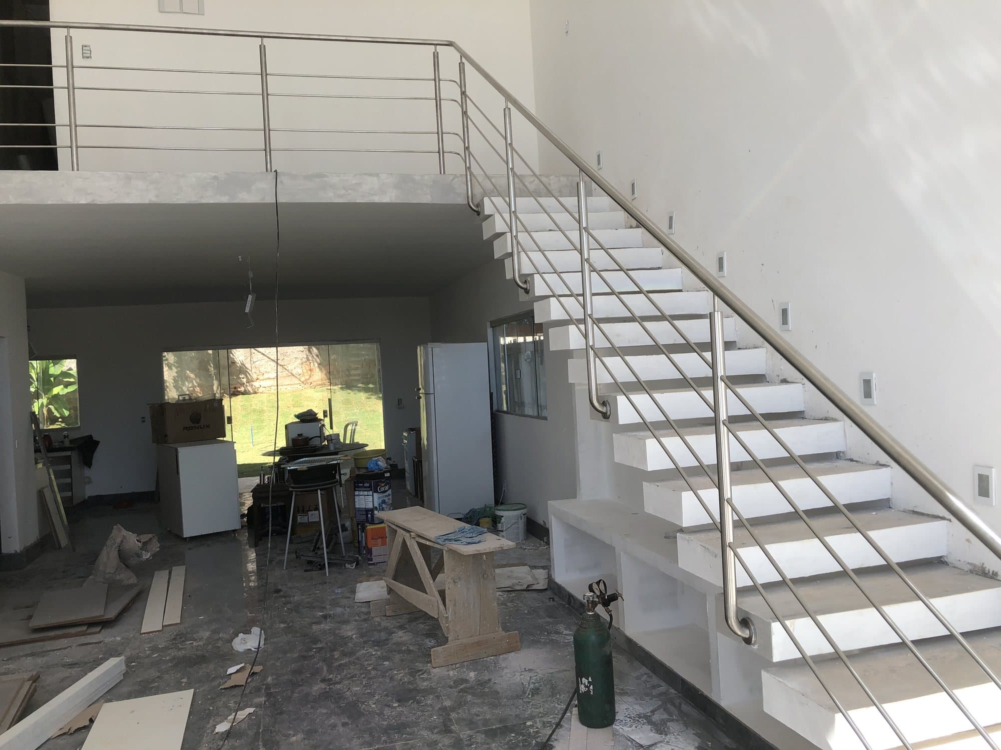 Escada e mezanino com guarda-corpo em aço inox, em casa em fase final de obra