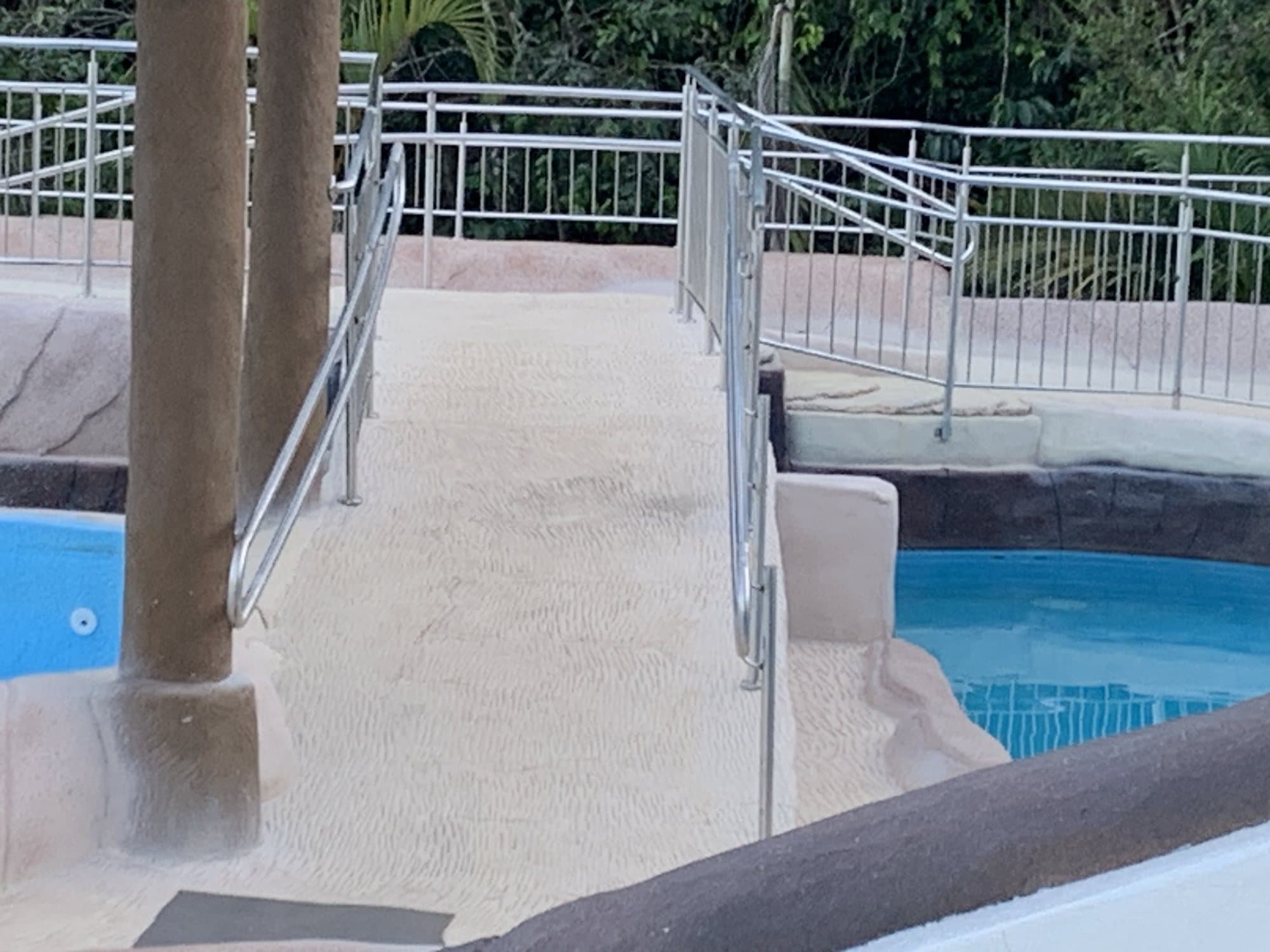 Rampa de acesso à piscina com guarda-corpos em aço inox dos dois lados