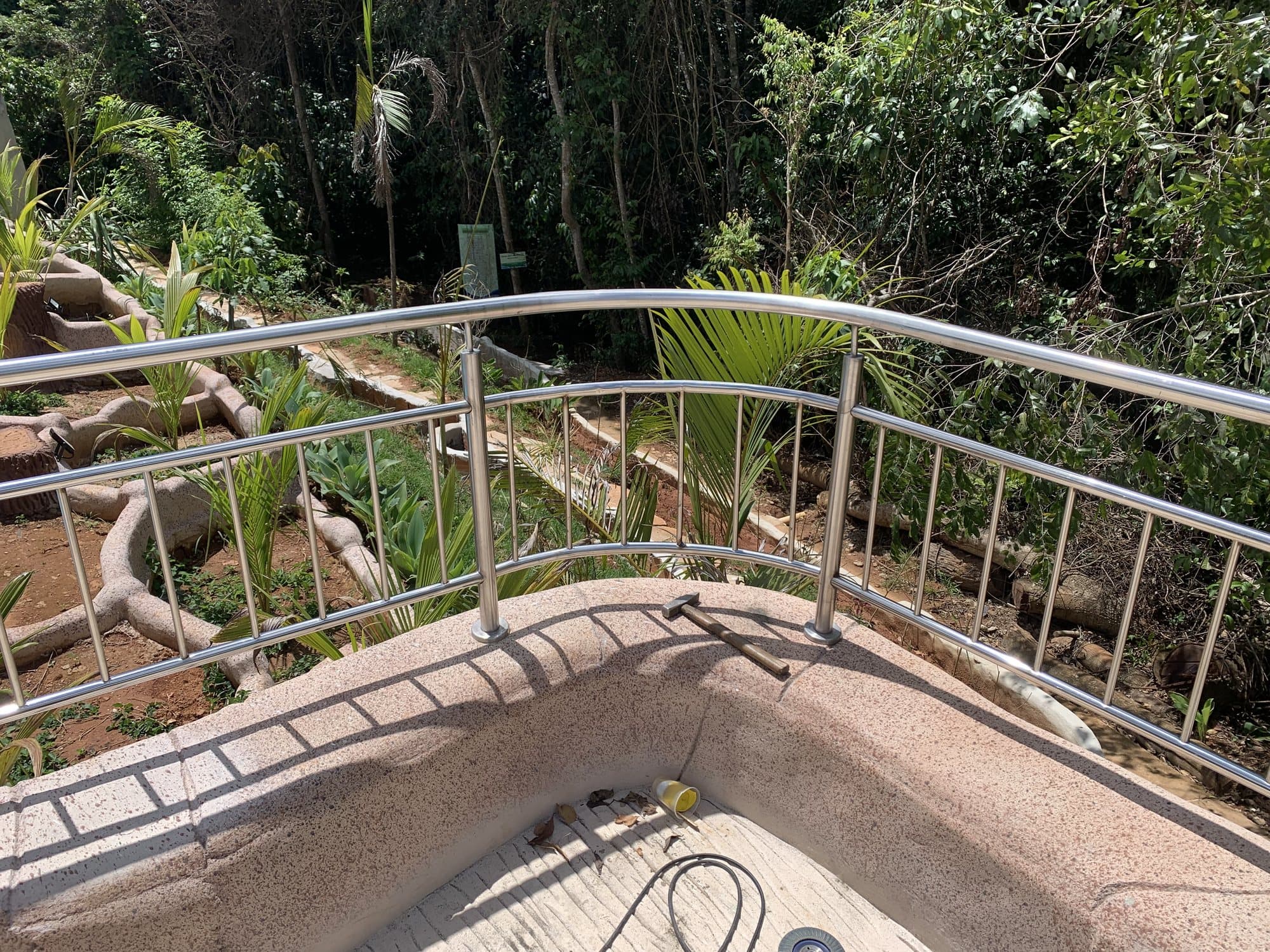 Guarda-corpo curvo em aço inox com balaústres verticais em mirante cercado por vegetação