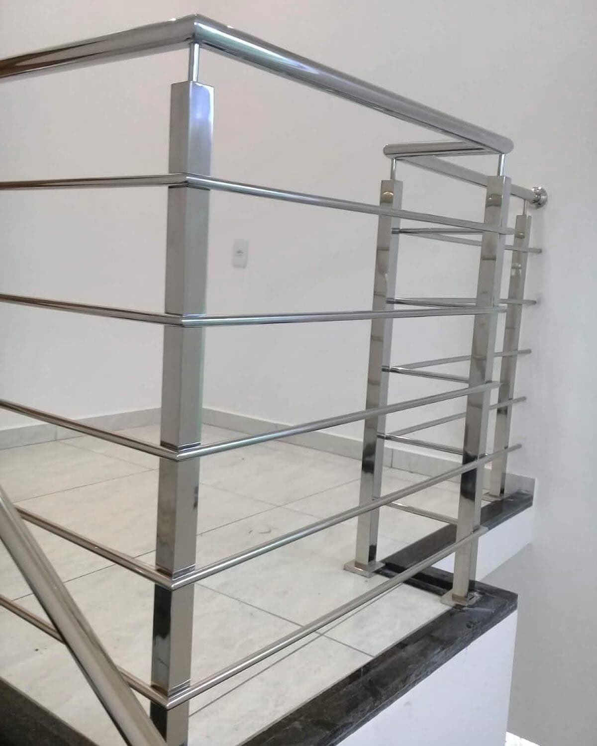 Guarda-corpo em aço inox polido com montantes quadrados e longarinas horizontais no topo de uma escada