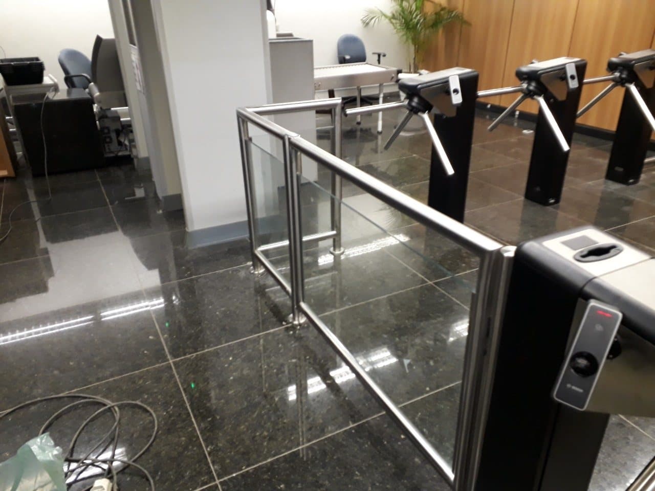 Fechamento em aço inox e vidro em L junto às catracas de acesso