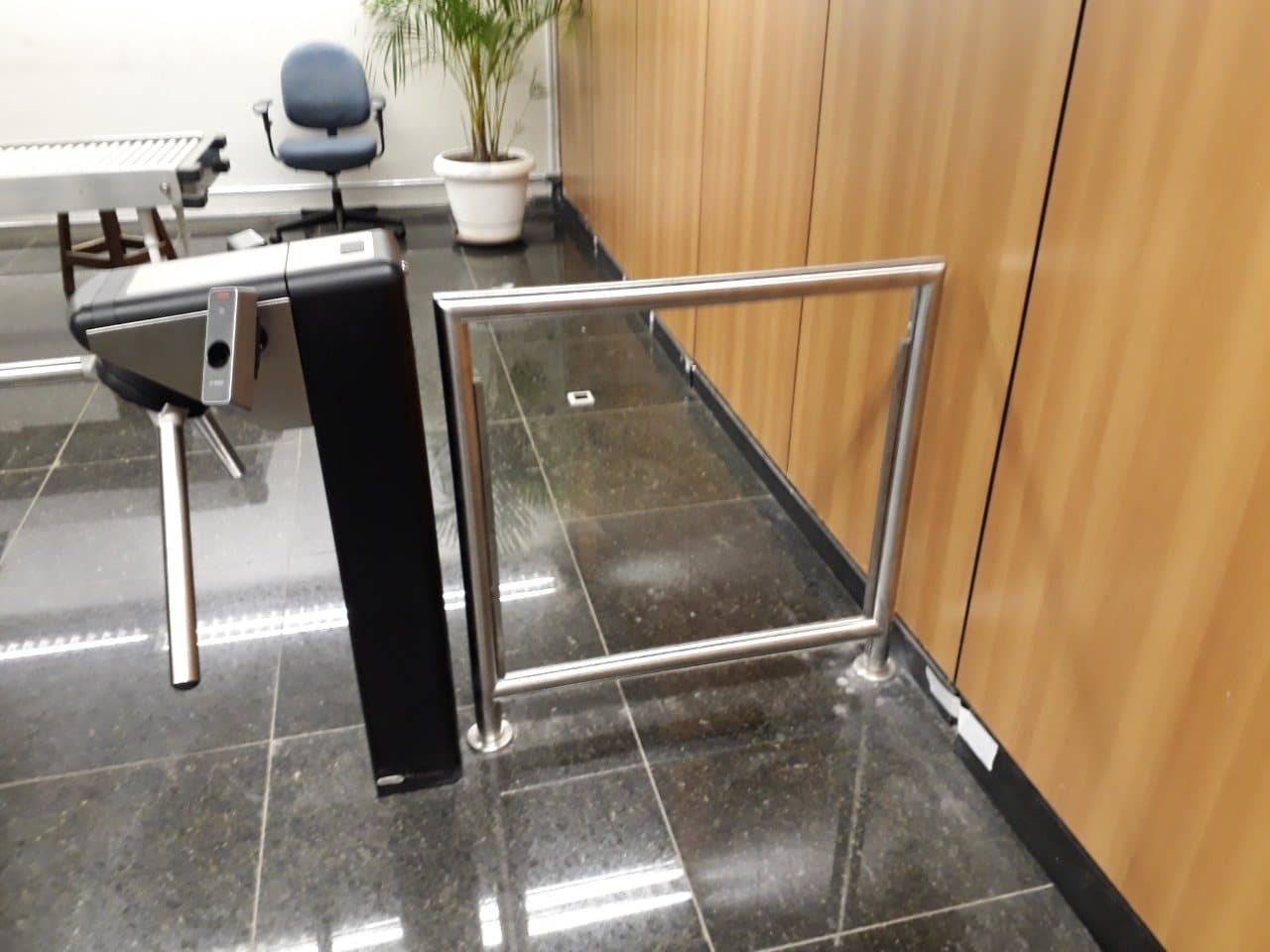 Módulo de guarda-corpo em aço inox com vidro entre a catraca e a parede de madeira