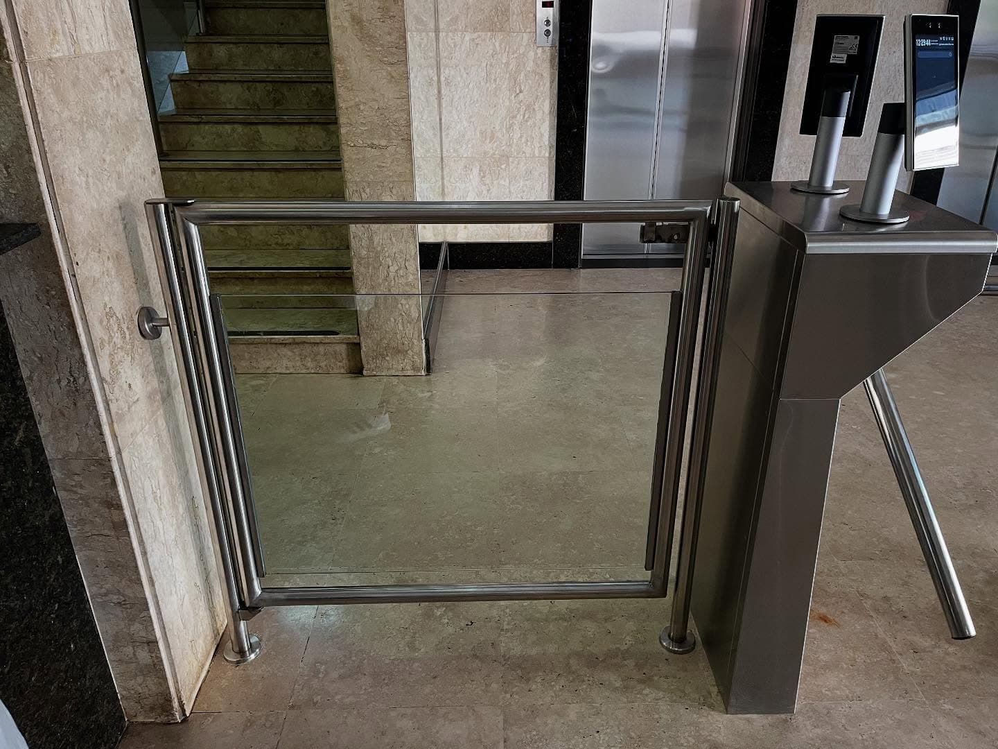 Fechamento em aço inox e vidro entre a catraca e a parede do hall