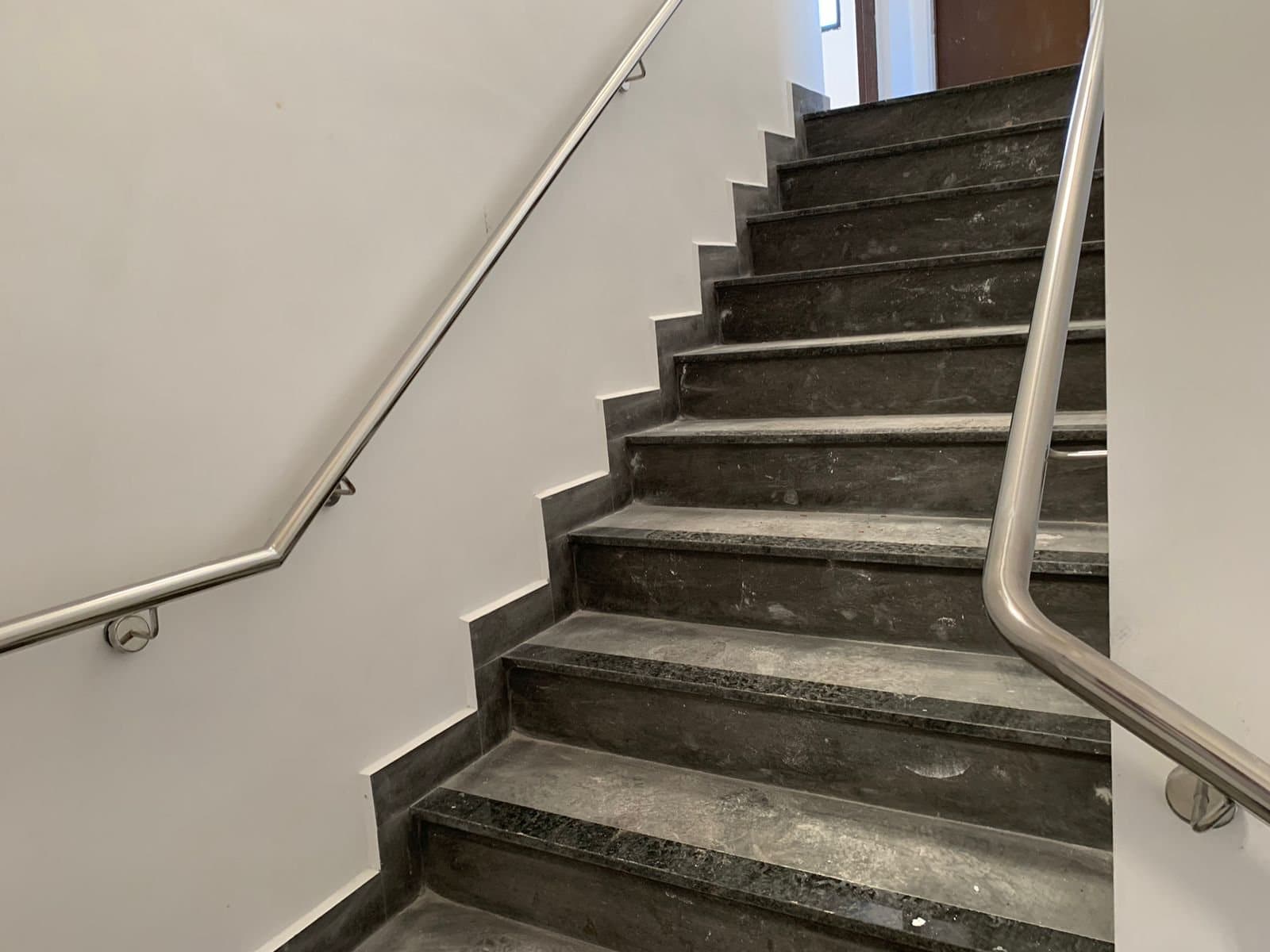 Corrimão de parede em aço inox acompanhando a mudança de lance da escada