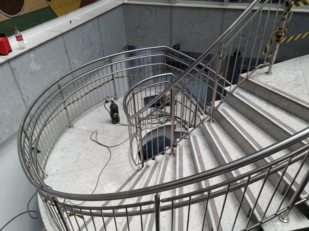 Patamar curvo da escada com guarda-corpo em aço inox e corrimão duplo