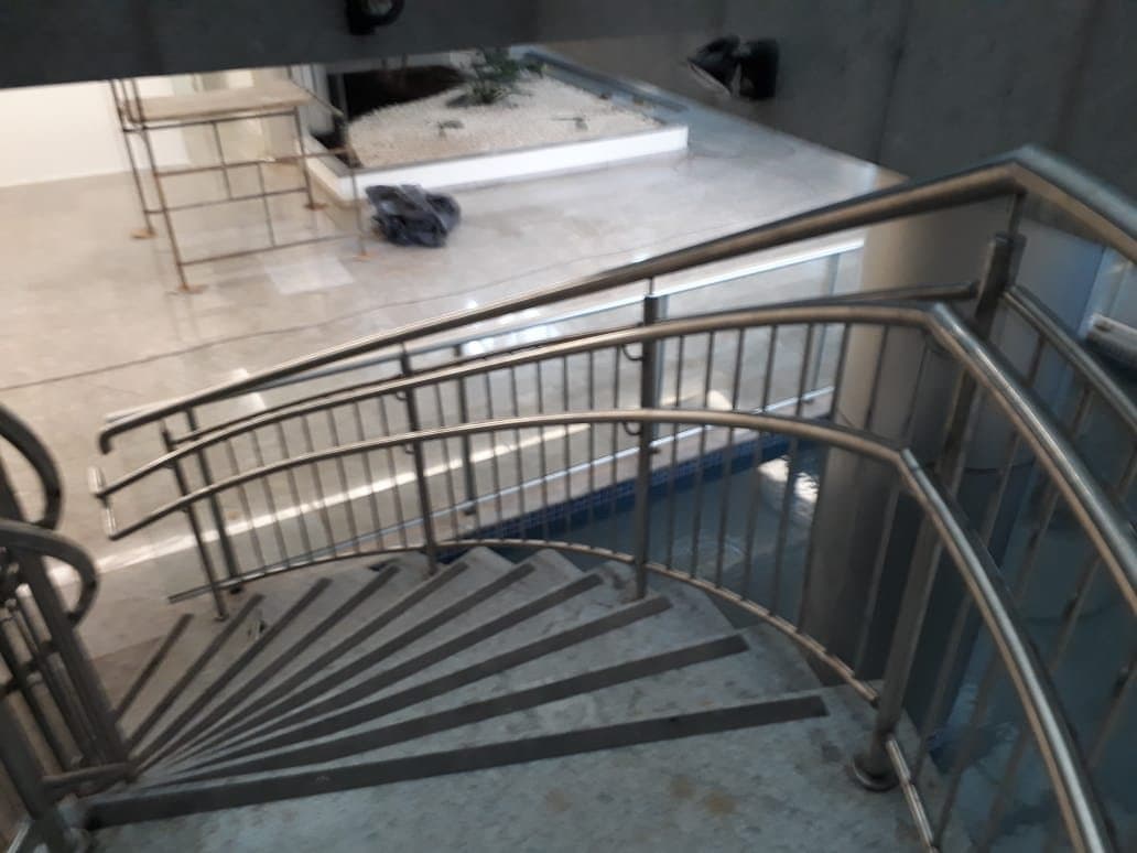 Encontro dos corrimãos curvos em aço inox no patamar da escada